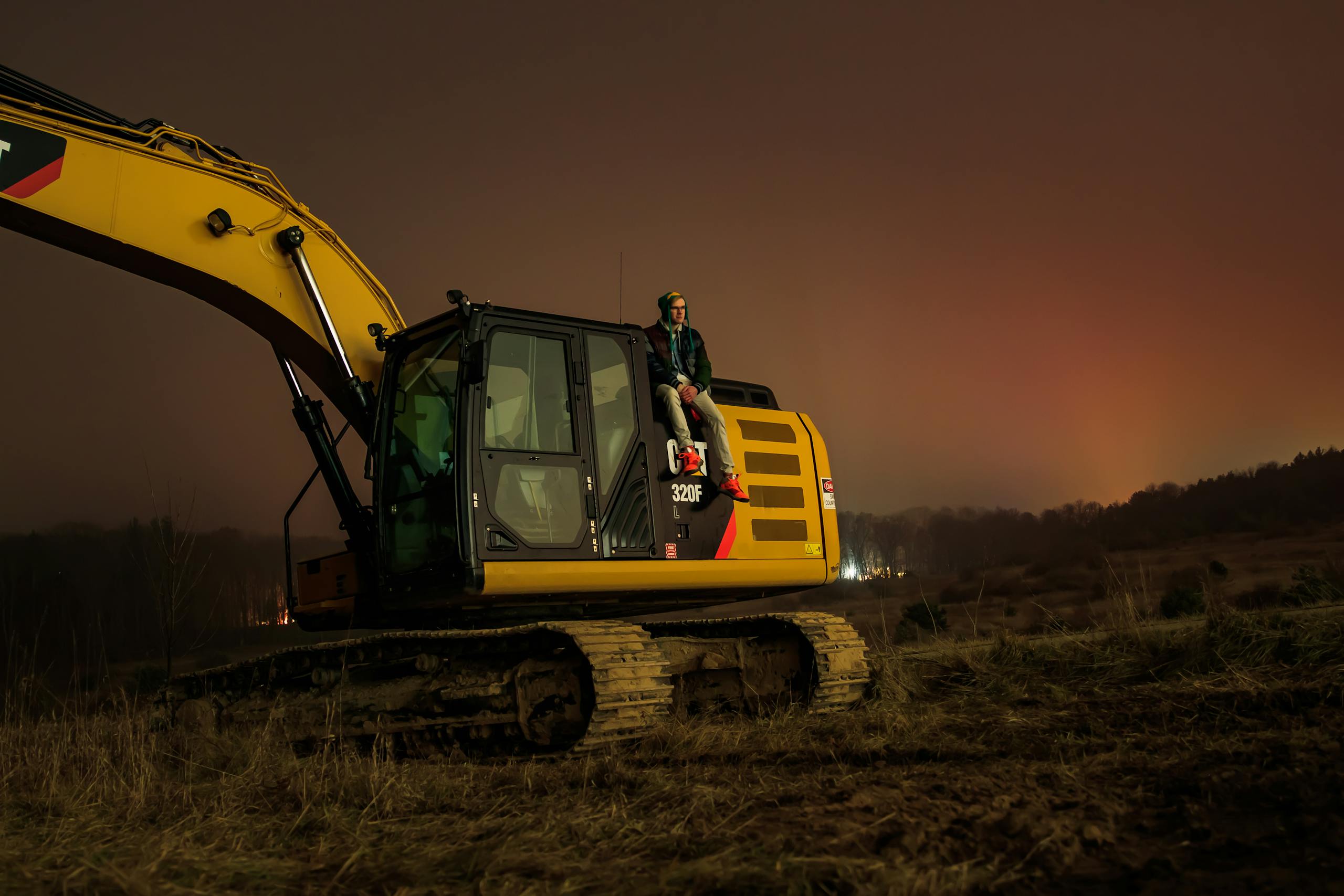 A person sitting on an excavator during the night in Greenville, Michigan. Tranquil rural setting.